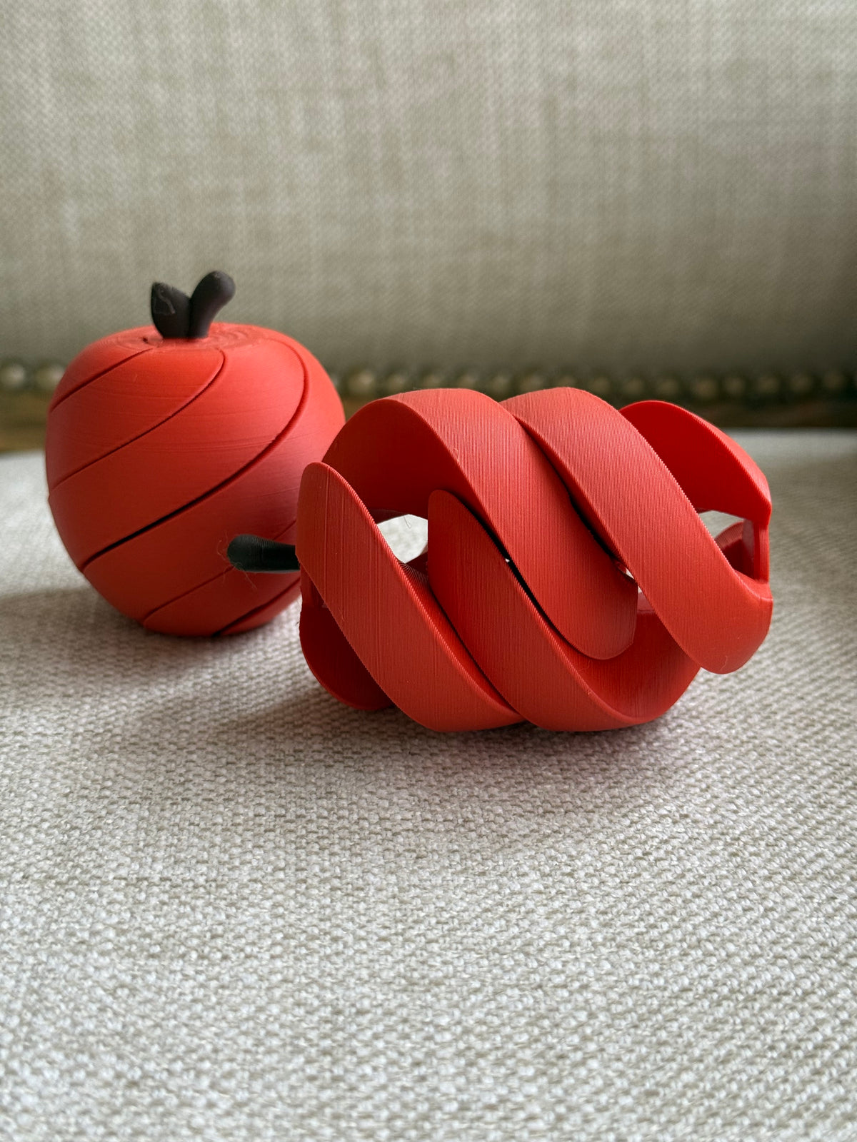 Apple fidget toy shown in its rounded and expanded spiral positions