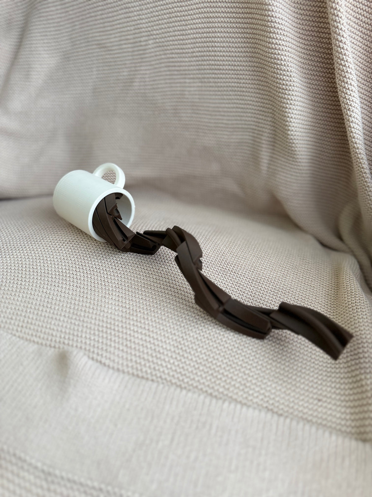 Pretend-play coffee cup tipped over with articulated coffee extending out