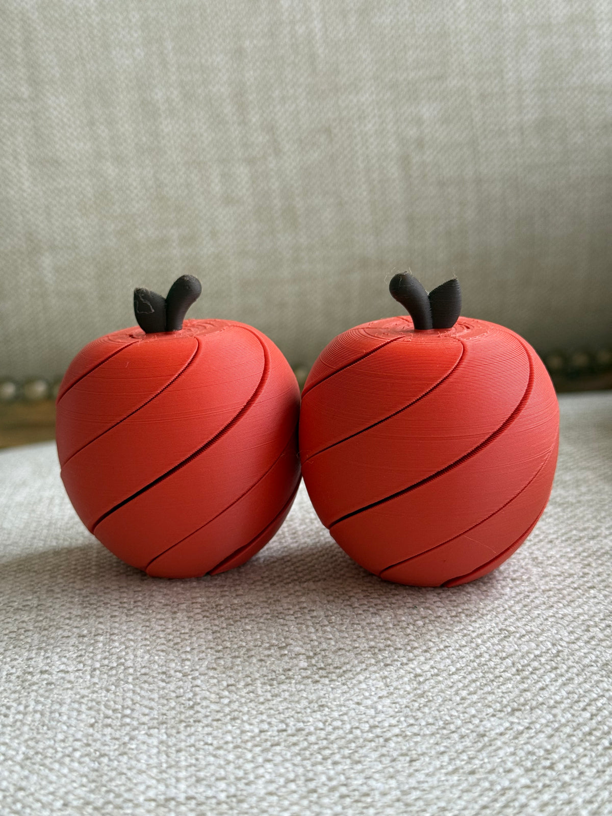 Two red apple-shaped play toys with spiral segments and dark stalks