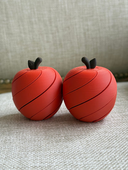 Two red apple-shaped play toys with spiral segments and dark stalks