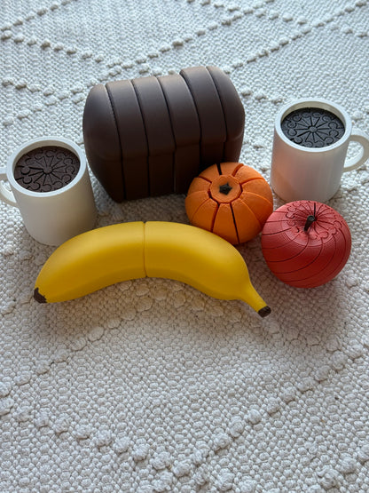 Yellow pretend-play banana styled with toy bread, fruit and coffee cups, sold separately